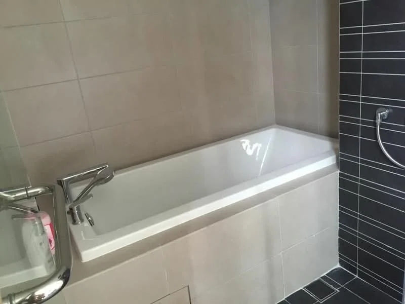 Bathroom features: built-in bathtub, chrome basin mixer faucet, tile cladding on walls, light grey tile flooring, dark grey accent wall, shower area with handheld shower, white bathtub, modern design; style: modern.