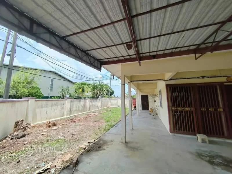 Exterior type: linked terrace house; features: concrete flooring, metal roof, exposed beams, fenced yard, landscaped garden area, utility poles visible, surrounding greenery, side walkway, covered patio area; style: modern.