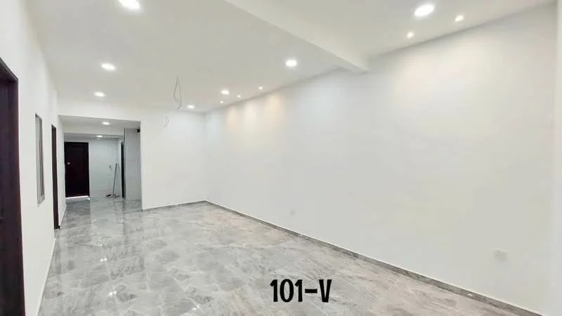 Room features: white painted walls, marble tile flooring, recessed LED downlights, ceiling with exposed wiring, open layout, no visible furniture, neutral color scheme, smooth ceiling; style: modern.