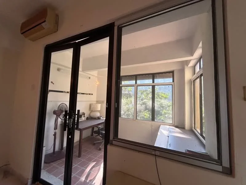 Room features: floor-to-ceiling windows, sliding glass door, wall-mounted split AC, desk with chair, tile flooring, natural light from windows, view of greenery; view: garden.