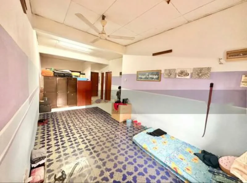 Room features: ceiling fan, white painted walls, purple accent wall, tiled flooring with geometric pattern, wooden storage cabinets, single bed with colorful bedding, floor mat, wall-mounted artwork, window with blinds.