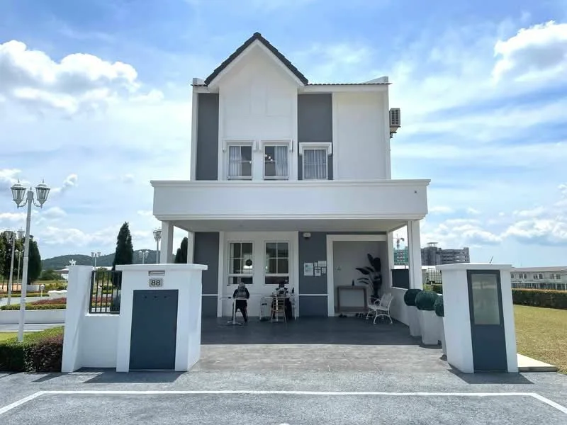 Exterior type: detached bungalow; features: white painted facade, grey accent wall, pitched tile roof, double-storey, manicured lawn, paved driveway, outdoor seating area, landscaped garden, modern light fixtures, front porch, large windows, security gate; style: modern.