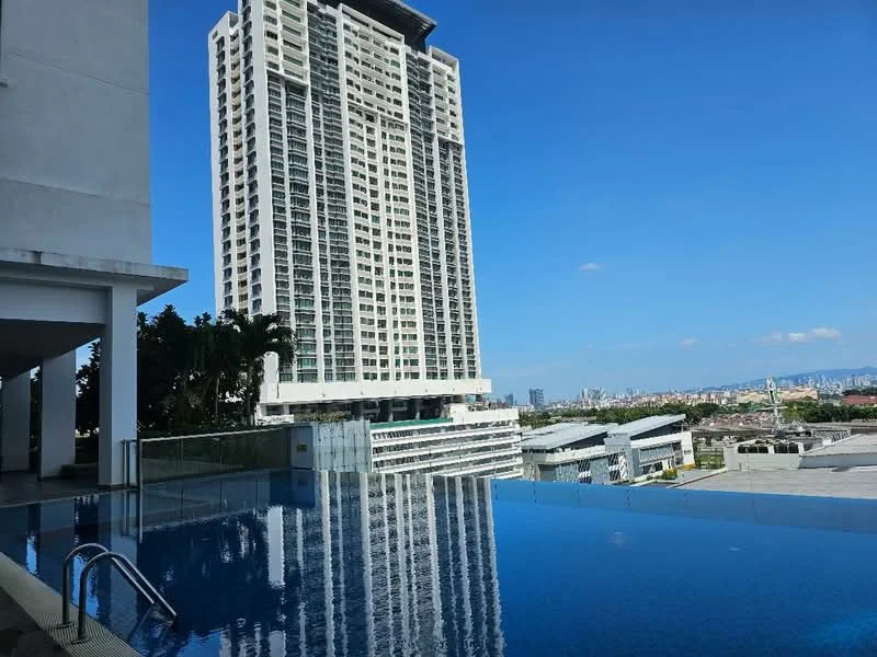 Exterior type: high-rise condominium; features: infinity pool, pool deck, glass railing, surrounding greenery, urban skyline view, modern architectural design, multiple storeys, balconies on upper floors; style: modern.