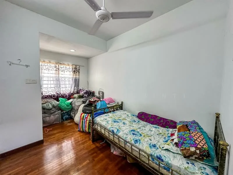 Bedroom features: wooden flooring, white painted walls, ceiling fan, single bed with floral bedding, double bed with colorful bedding, window with sheer curtains, decorative pillows, cluttered with personal items.