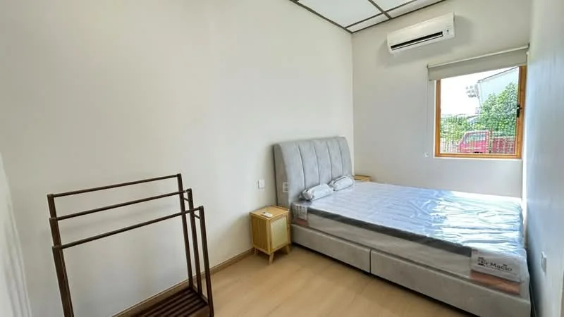 Bedroom features: queen-size bed with upholstered headboard, light grey bed frame, wooden bedside table, wall-mounted air conditioning unit, window with roller blinds, laminate flooring, clothes rack, white painted walls; style: modern; view: garden.