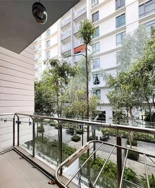 Room features: glass railing, concrete flooring, outdoor space, view of greenery, trees visible, surrounding buildings, balcony area, laundry line; style: modern; view: garden.