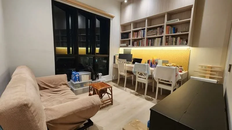 Living features: beige fabric sofa, wooden coffee table, built-in shelving unit with books, desk with multiple chairs, wall-mounted lighting, large windows with black frames, light wood flooring, yellow backlit panel behind shelving; style: modern; view: city.