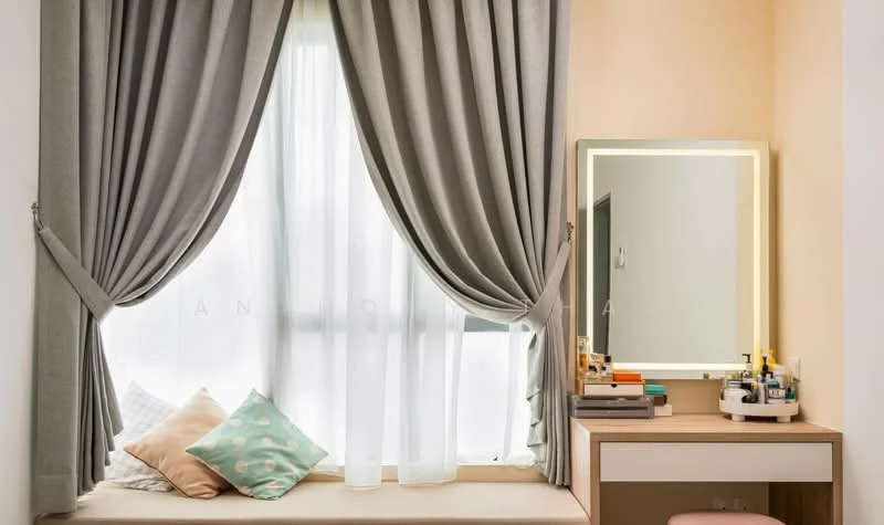 Room features: large window with sheer curtains, grey drapes, window seat with cushions, light wood vanity table, framed mirror with LED backlighting, various skincare and cosmetic products on the vanity, decorative pillows, light peach painted wall; style: modern.