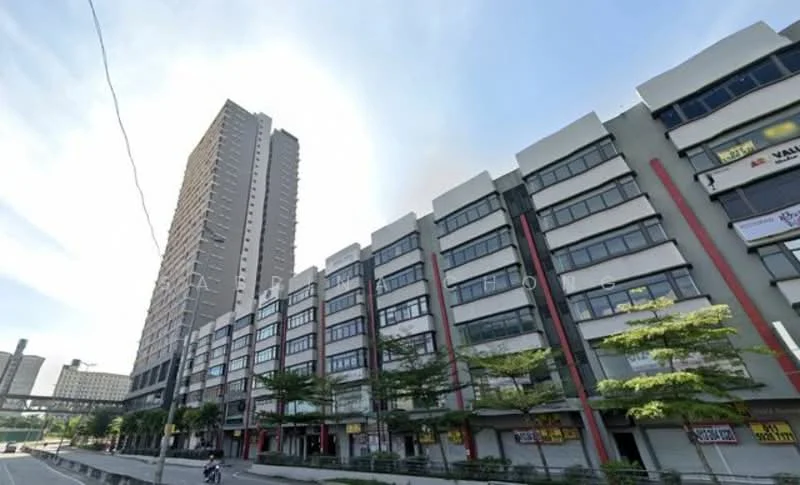 Exterior type: mid-rise condominium; features: glass curtain wall, red accent panels, multiple storeys, balconies on upper floors, commercial units on ground floor, manicured landscaping, surrounded by greenery, urban context with main road, visible signage on commercial units; style: modern.