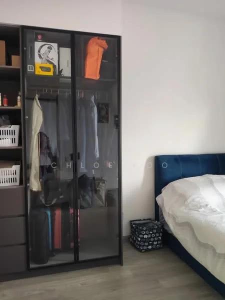 Bedroom features: blue upholstered bed, white bedding, glass-front wardrobe, clothes hanging in wardrobe, suitcases visible, black storage box, wooden flooring, white painted walls; style: modern.