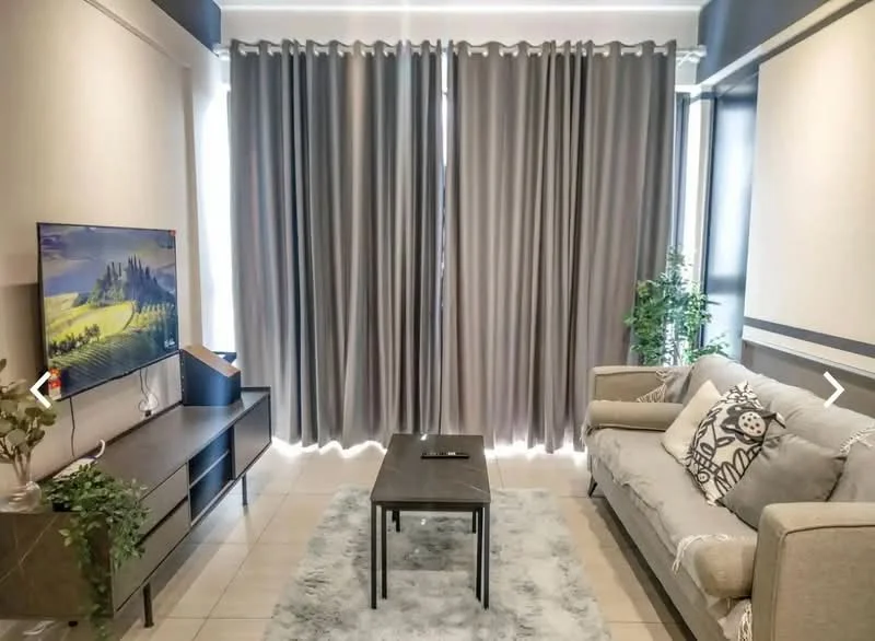 Living features: grey fabric sofa, decorative throw pillows, wooden coffee table, TV console with storage, wall-mounted TV, light grey area rug, floor-to-ceiling windows, sheer curtains, potted plant, decorative plant on console; style: modern.