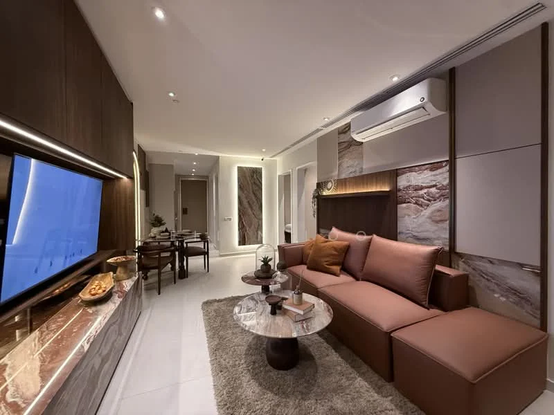 Living features: L-shape sectional sofa in brown, coffee table with marble top, wall-mounted TV, TV console with wood finish, recessed downlights, 1 wall-mounted split AC, decorative wall with stone cladding, area rug, decorative plants, dining area in background with wooden dining table and chairs; style: modern.