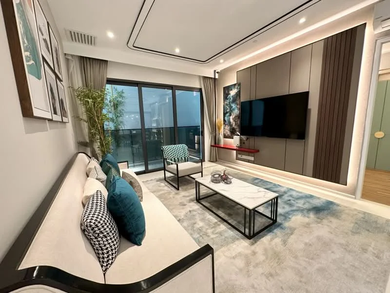 Living features: light grey walls, white ceiling with recessed lighting, large floor-to-ceiling windows, black framed TV console, wall-mounted TV, marble coffee table, beige sofa with black trim, decorative cushions in blue and black, area rug with abstract pattern, indoor plant, wooden flooring; style: modern; view: city.