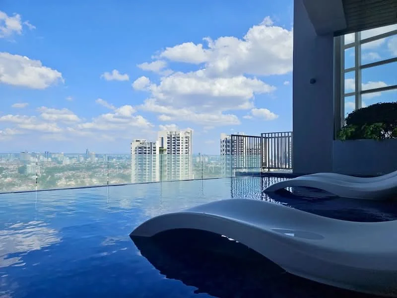 Exterior type: high-rise condominium; features: infinity pool, pool deck with loungers, glass railing, city skyline view, surrounded by urban landscape, sunny weather, cloudy sky; style: modern.