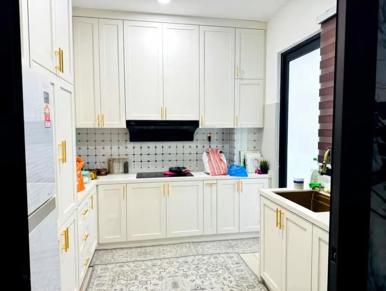 Kitchen features: white shaker cabinets, gold hardware on cabinets, stainless-steel sink, chrome pull-down faucet, white countertop, white tiled backsplash with black accents, built-in oven, stainless-steel fridge, decorative floor tiles with geometric pattern, window with horizontal blinds, kitchen island, various kitchen items on countertop; style: modern.