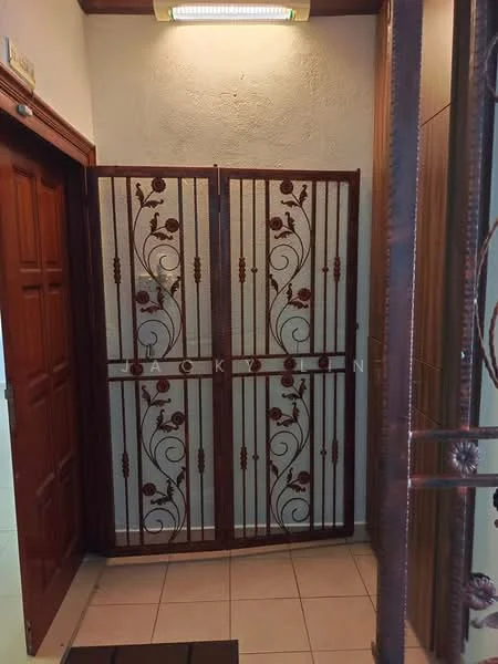 Room features: decorative metal grille door with floral pattern, wooden main door with panel design, cream textured walls, tiled flooring in beige, overhead light fixture, corner wall with decorative trim; style: traditional.