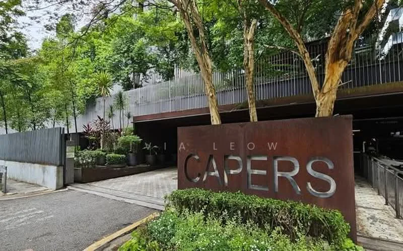Exterior type: low-rise apartment block; features: metal signage with the word 'CAPERS', manicured landscaping with shrubs, paved walkway, surrounded by mature trees, modern facade, entrance driveway; style: modern.