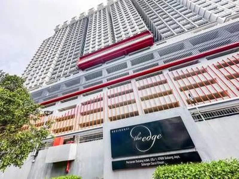 Exterior type: high-rise condominium; features: glass curtain wall, red accent panels, multiple balconies, parking deck, signage at entrance, landscaped greenery at base; style: modern.