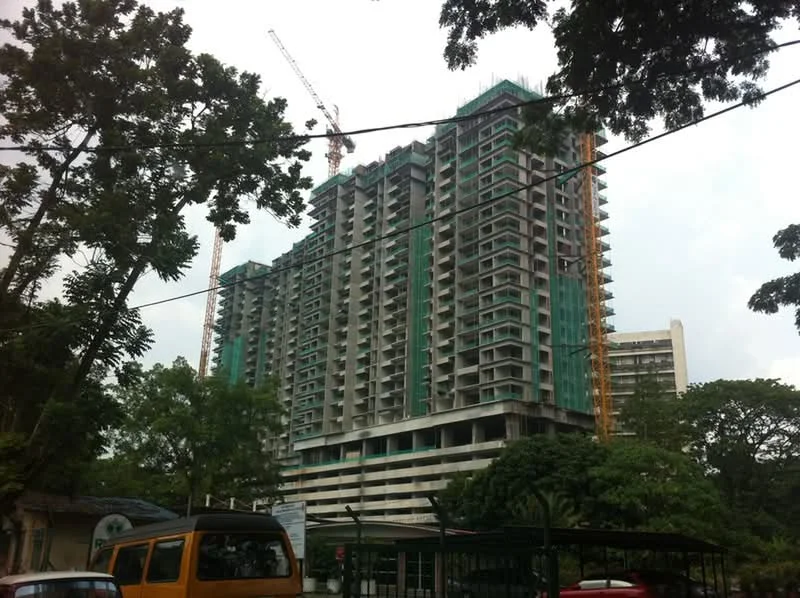 Exterior type: high-rise condominium; features: glass curtain wall, green construction netting, construction cranes, multiple balconies, concrete facade, surrounded by trees, adjacent to a road, multi-storey structure; style: modern.