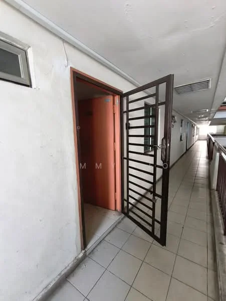 Room features: white painted walls, grey tiled flooring, metal security door, open door, window with metal grille, hallway with railing, fluorescent ceiling lights.