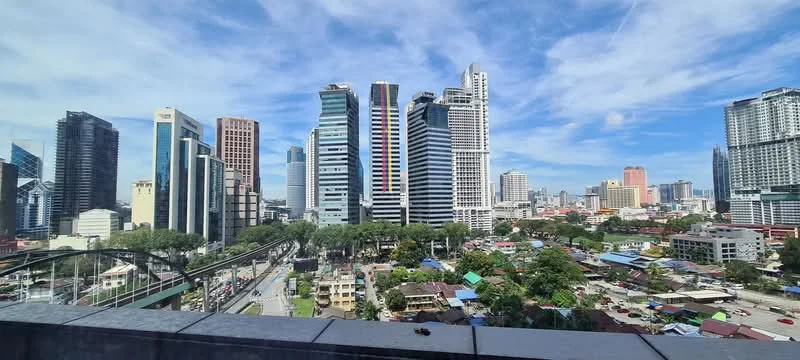 Exterior type: high-rise condominium; features: glass curtain wall, recessed balconies, urban skyline view, surrounded by mature greenery, adjacent to highway; style: modern.