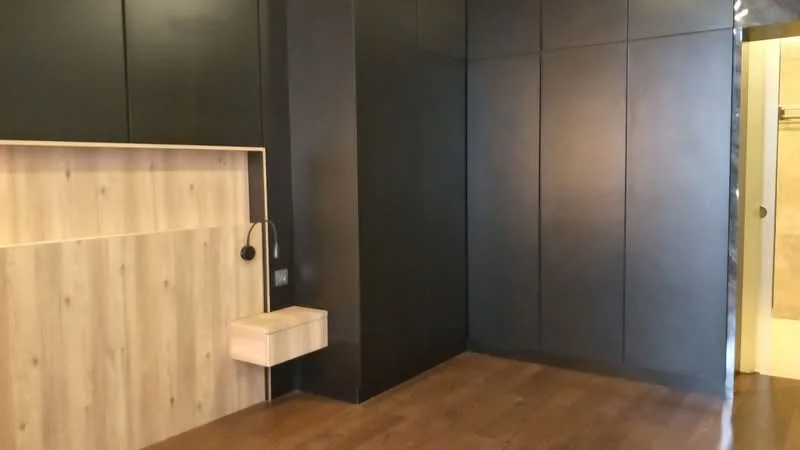 Room features: dark painted walls, wood panel accent wall, wooden flooring, built-in wall cabinet, suspended drawer unit, recessed lighting, neutral color palette; style: modern.