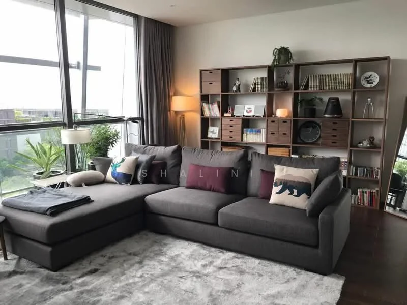 Living features: L-shape sectional sofa in grey, decorative throw pillows with animal prints, area rug with soft texture, wooden shelving unit with books and decor, floor-to-ceiling windows, curtains in light fabric, indirect lighting from floor lamp, houseplants in ceramic pots, wooden flooring, coffee table, wall-mounted decor; style: modern; view: garden.