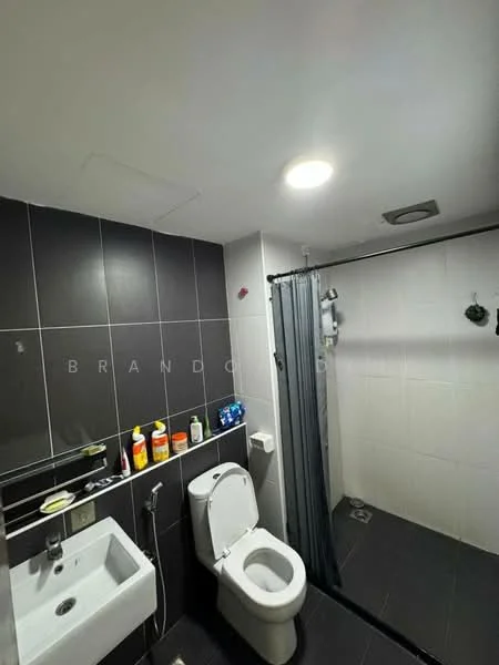 Bathroom features: white toilet, single-sink vanity with mirror, chrome basin mixer faucet, shower area with glass partition, grey wall tiles, black floor tiles, recessed ceiling lights, shower head, shower curtain, toiletries on countertop; style: modern.