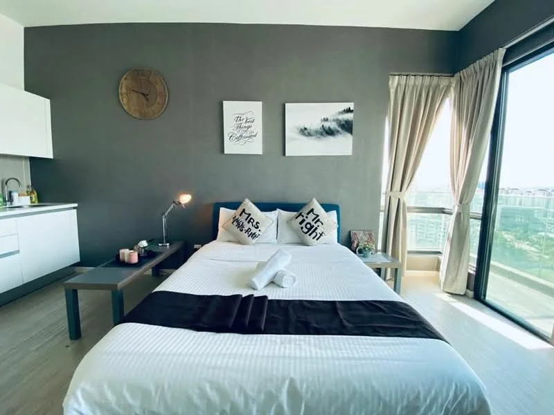 Bedroom features: king-size bed with white bedding, blue upholstered headboard, two decorative pillows with text, wooden side tables, table lamp, wall clock, grey accent wall, floor-to-ceiling windows, curtains, wooden flooring, framed artwork on walls; style: modern; view: city.