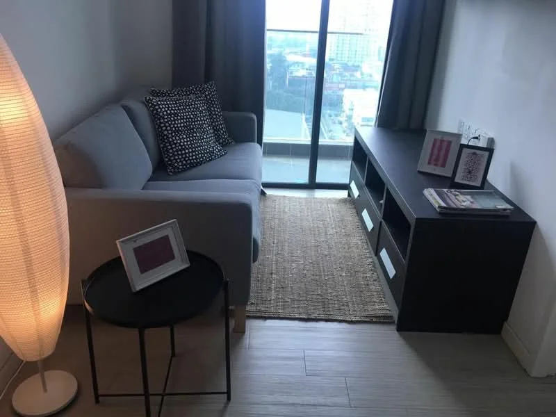 Living features: grey fabric sofa, black and white polka dot throw pillow, black side table, floor lamp with a cylindrical shade, wooden TV console, decorative items on console, area rug, large window with city view, curtains, light wood flooring; style: modern; view: city.