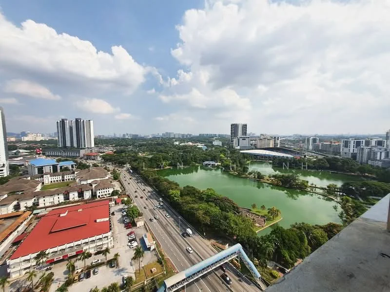 Exterior type: high-rise condominium; features: city skyline view, surrounded by greenery, large lake, nearby sports complex, main road visible, urban landscape, multiple high-rise buildings, open sky, well-maintained landscaping; style: modern.