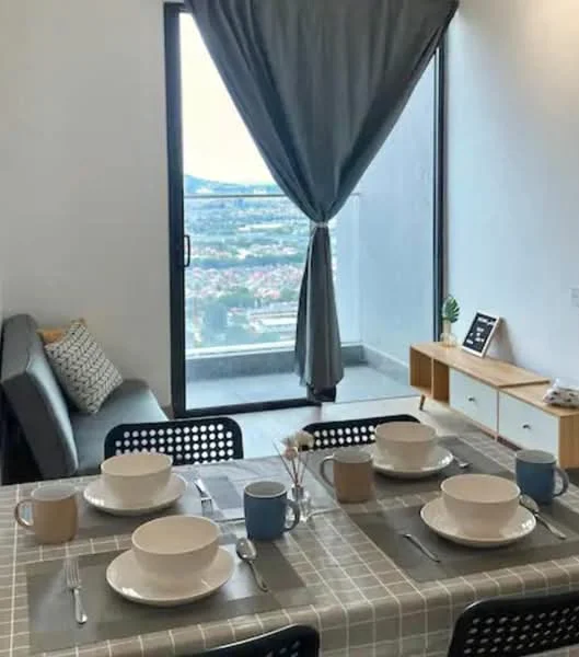 Dining features: 4-seater dining table, grey tablecloth, white ceramic plates, blue ceramic mug, brown ceramic mug, cutlery set, grey sofa, decorative cushion, floor-to-ceiling window, curtain, wooden sideboard, decorative items on sideboard; style: modern; view: city.
