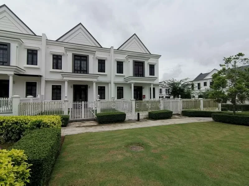 Exterior type: linked terrace house; features: white painted facade, pitched tile roof, manicured lawn, hedge landscaping, stone-paved walkway, fenced front yard, multiple storeys, front porch, large windows, symmetrical design; style: modern.