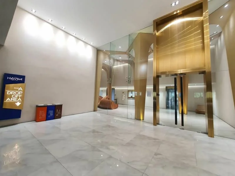 Exterior type: main entrance gate; features: glass entrance doors, marble flooring, gold accent wall, recessed lighting, signage for drop-off area, seating area, decorative wall feature, modern design; style: modern.