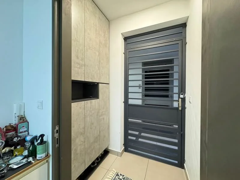 Room features: grey metal security door, light beige tiled flooring, built-in cabinetry with textured finish, wall-mounted storage unit, neutral wall colour, decorative mat at entrance; style: modern.