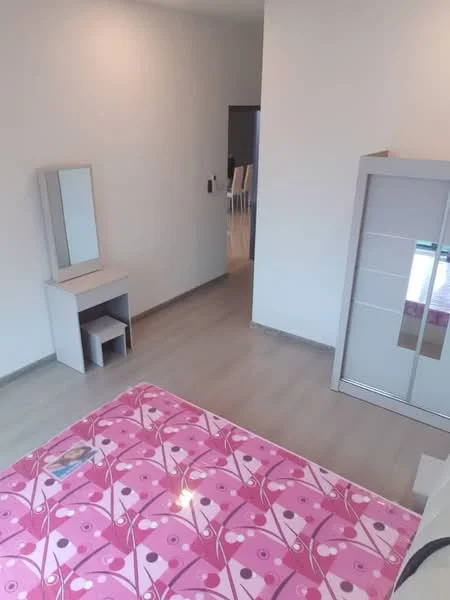 Bedroom features: pink floral patterned bedspread, wooden flooring, built-in wardrobe with sliding doors, dressing table with mirror, small stool, neutral painted walls, natural light from window, minimalist decor; style: modern.