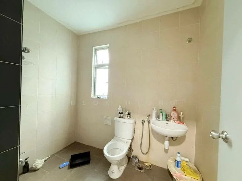 Bathroom features: white tiled walls, grey tile flooring, one-piece toilet, wall-mounted sink, mirror above sink, shower area with no door, window for natural light, various toiletries on sink, black mat on floor.