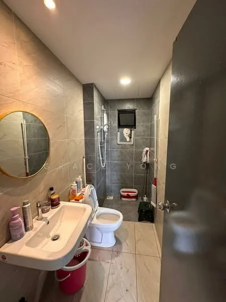 Bathroom features: grey tiled walls, white ceramic floor tiles, single-sink vanity with integrated basin, round mirror with gold frame, chrome basin mixer faucet, toilet, shower with glass partition, wall-mounted shower head, handheld shower, towel rack, window for natural light, storage shelf, various toiletries on vanity; style: modern.
