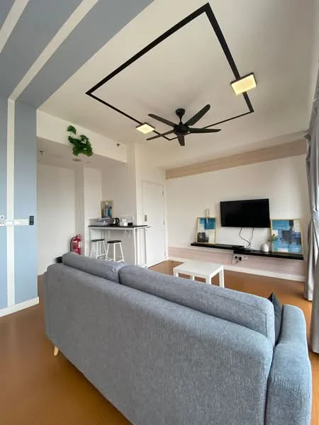 Living features: grey fabric 3-seater sofa, white coffee table, wall-mounted TV, TV console, 5-blade ceiling fan with light, recessed downlights, light grey accent wall, white walls, wooden flooring, decorative plant on ceiling, curtains, bar counter with stools; style: modern.