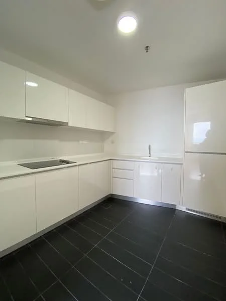 Kitchen features: white glossy cabinetry, stainless-steel sink, chrome faucet, built-in cooktop, white countertop, black tile flooring, recessed ceiling lights, integrated refrigerator, wall-mounted range hood; style: modern.
