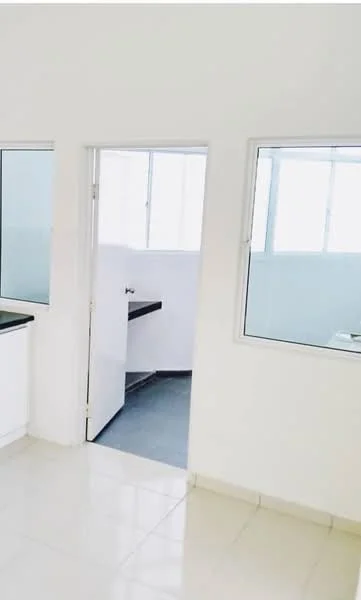 Room features: white painted walls, tile flooring, two windows, doorway leading to another room, black countertop, grey flooring in adjacent room; style: modern.