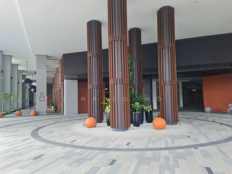 Exterior type: clubhouse; features: tall cylindrical columns with wood cladding, decorative orange and grey wall, paved flooring with geometric patterns, landscaped planters with greenery, large decorative spheres in orange and white, overhead lighting fixtures, open entrance area, modern architectural design; style: modern.