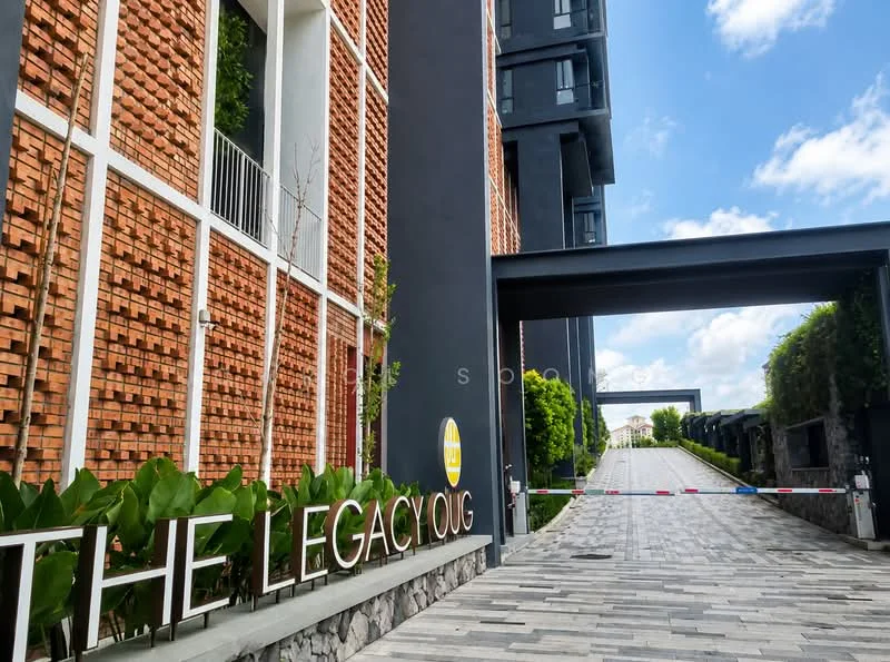 Exterior type: low-rise apartment block; features: exposed brick facade, grey painted walls, paved driveway, landscaped greenery, signage at entrance, guard house at entrance; style: modern.