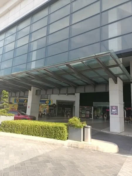 Exterior type: commercial building; features: glass curtain wall, canopy over entrance, manicured hedges, paved walkway, visible storefronts, parking area, signage on facade; style: modern.