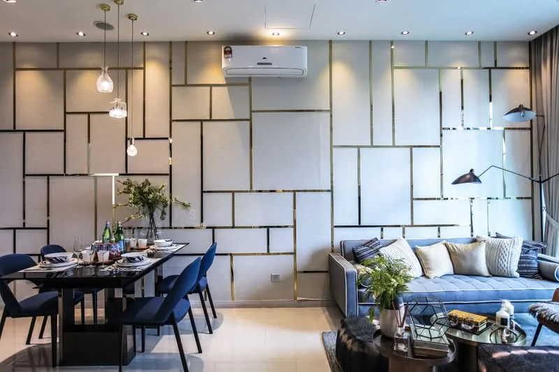 Living features: sofa in grey fabric, decorative cushions in various colors, coffee table with geometric design, area rug with textured pattern, wall-mounted TV, floor lamp with adjustable arm, 5-blade ceiling fan with integrated LED light, wall with textured panels and gold accents, large windows with sheer curtains, dining table with 6 blue upholstered chairs, decorative vase with flowers on dining table, table setting with plates and glasses; style: modern.