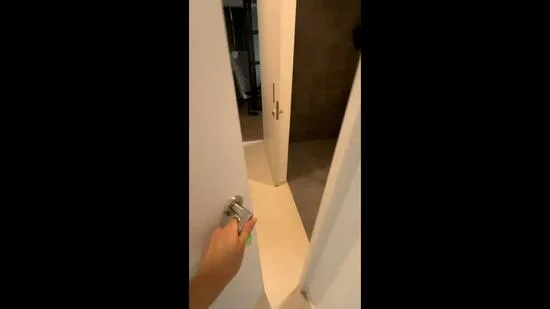 Room features: white painted walls, light-colored flooring, door with modern handle, neutral tile flooring, shower area visible, minimalist design; style: modern.