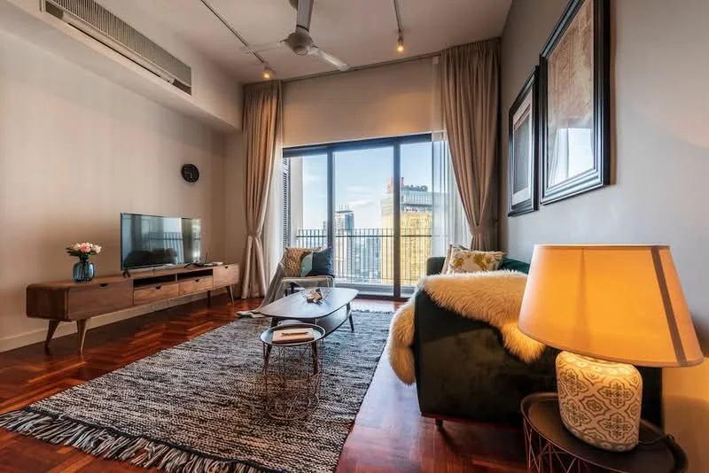 Living features: parquet wood flooring, floor-to-ceiling windows, city view, 3-seater fabric sofa in dark green, coffee table, TV console, wall-mounted TV, area rug with geometric pattern, decorative lamp, curtains, ceiling fan with light, framed artwork; style: modern.