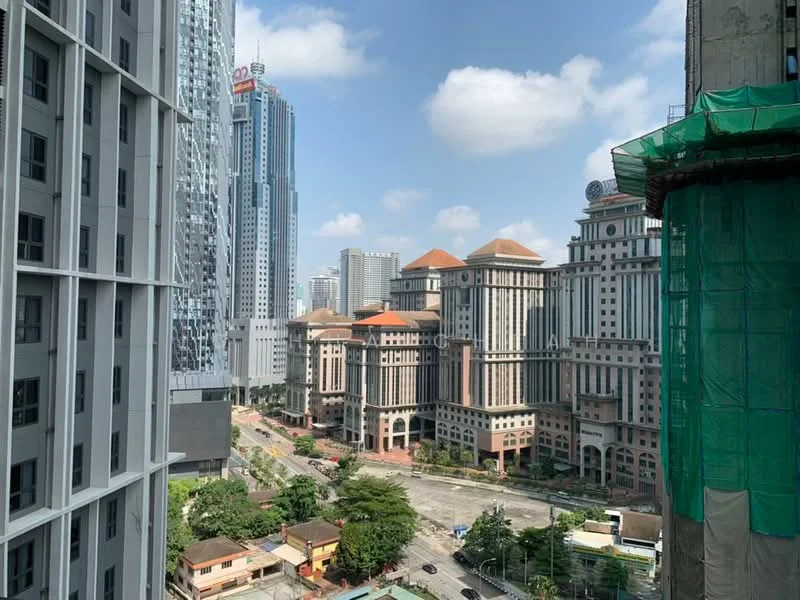 Exterior type: high-rise condominium; features: city skyline view, surrounded by modern buildings, green construction netting, paved road, landscaped greenery, multiple high-rise structures, prominent architectural features on buildings, clear blue sky; style: modern.