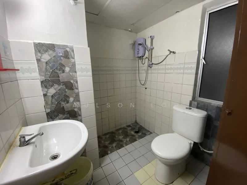 Bathroom features: white ceramic toilet, single-sink vanity with chrome faucet, shower area with wall-mounted water heater, grey and white tiled walls, grey and white tiled flooring, window for natural light, mirror above sink, shower curtain rod.