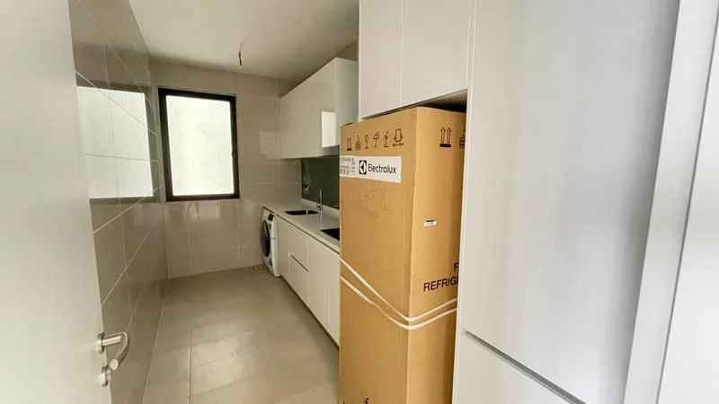 Kitchen features: white cabinetry, black countertop, built-in oven, stainless-steel fridge, single-bowl stainless-steel sink, chrome pull-down faucet, ceramic tile flooring, white tiled walls, window with no visible treatment, washing machine, box for refrigerator, open layout; style: modern.